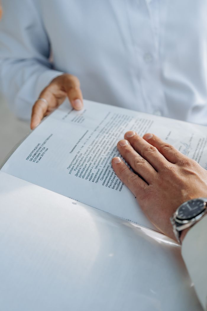 Offerings Close-up of hands reviewing a business agreement document. Professional setting.